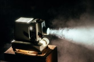 Vintage projector casting light beam in dark room.