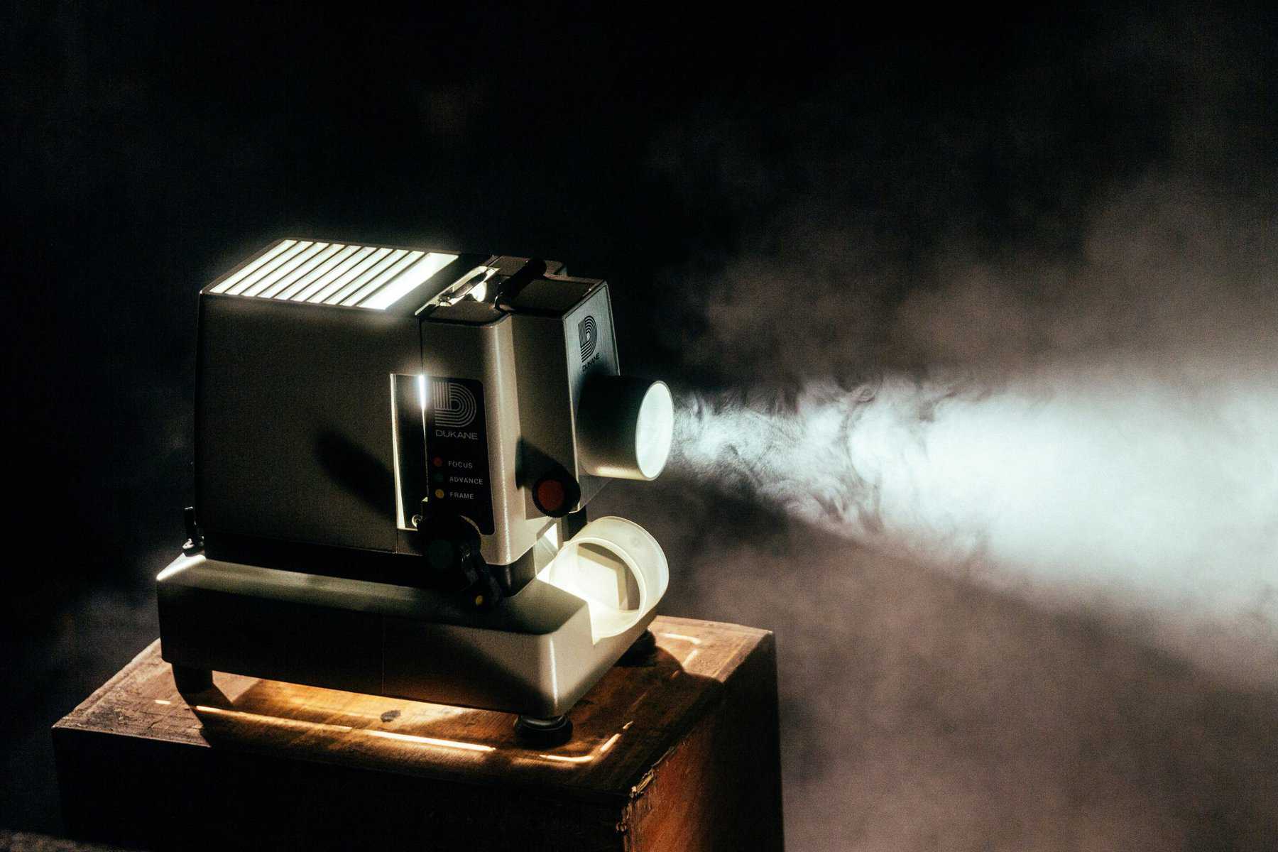 Vintage projector casting light beam in dark room.