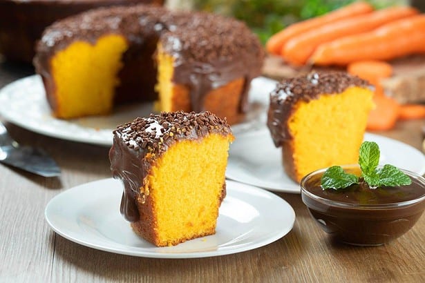 close up piece brazilian carrot cake with chocolate frosting wooden table with carrots background