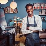 portrait handsome african barista standing with crossed arms counter trendy coffee shop