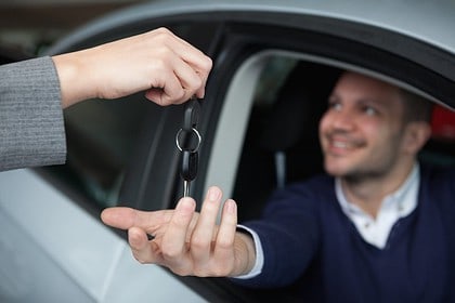 man receiving car keys while sitting in his car