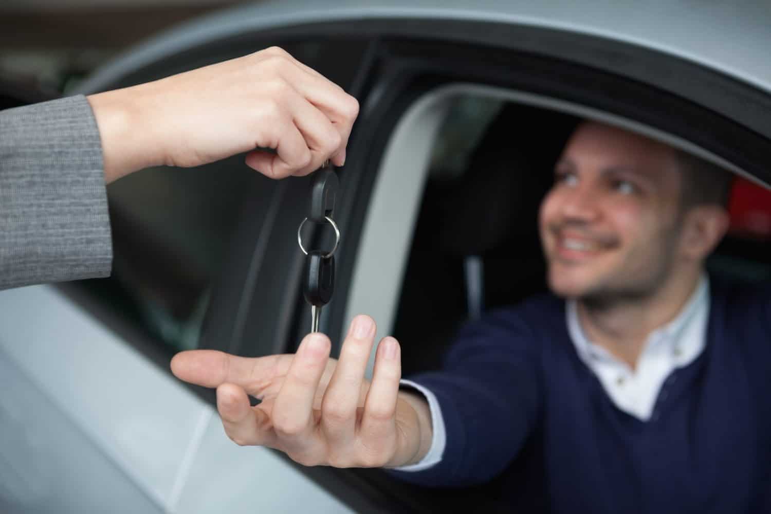 man receiving car keys while sitting in his car