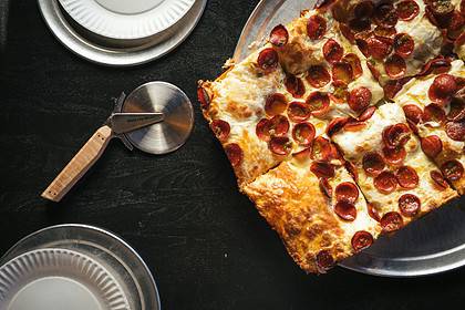 Detroit-style pepperoni pizza on dark table setting.