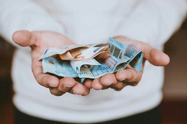 Hands holding crumpled Euro banknotes, concept of financial inheritance tax.