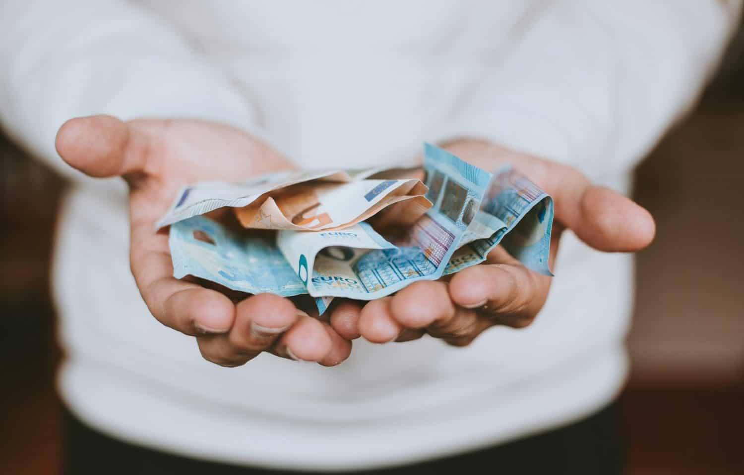 Hands holding crumpled Euro banknotes, concept of financial inheritance tax.